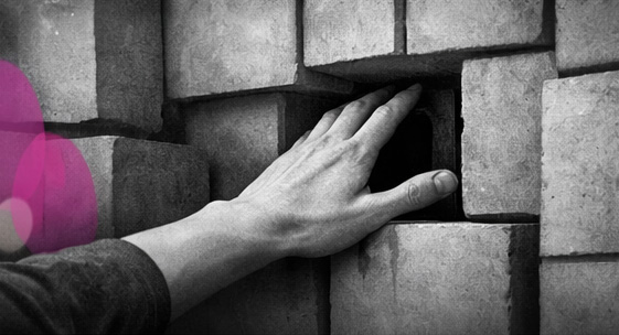 Main humaine traversant un mur de blocs symbolisant le contrôle social, avec accents rose et violet Mimethys.