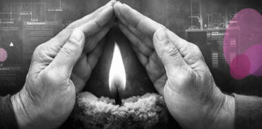 Mains protégeant une petite flamme du vent, avec accents rose et violet Mimethys.