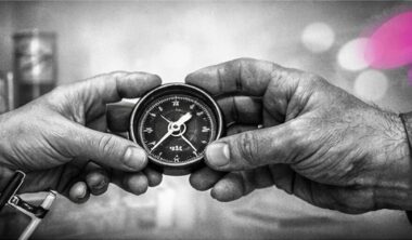 Deux mains tenant ensemble une boussole, l’une appartenant à un chercheur et l’autre à un clinicien, en noir et blanc avec accents rose et violet Mimethys.