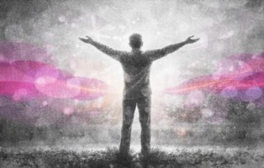 Personne debout, bras ouverts vers le ciel dans une posture d’élan et de liberté.