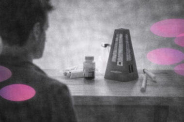 Personne face à un métronome posé sur une table, en noir et blanc, avec accents rose et violet.