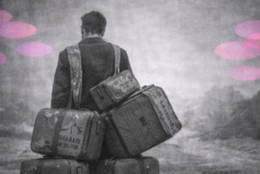 Une personne portant plusieurs valises anciennes marquées d’initiales familiales, en noir et blanc avec accents rose et violet.