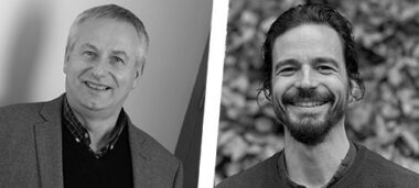 Image en noir et blanc montrant deux personnes en dialogue autour d’un schéma du monde, illustrant les regards croisés entre écologie, clinique et lien, avec des touches rose/violet inspirées des œufs Mimethys.