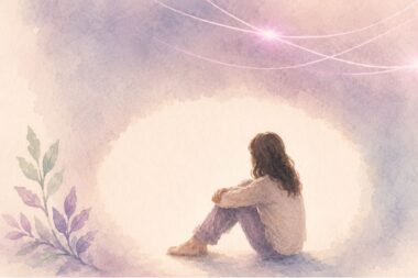 Silhouette en ombre d’une personne assise seule au sol, éclairée par un halo de lumière, symbolisant la honte et l'isolement.