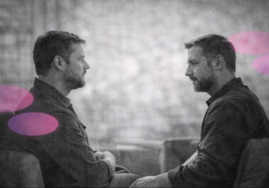 Deux hommes en séance de thérapie, se regardant dans un cabinet, en noir et blanc avec touches rose et violet. »