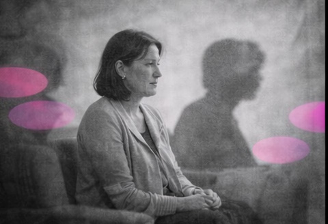 Thérapeute debout dans son cabinet, entourée d’ombres légères, en noir et blanc avec accents rose et violet.