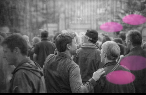 Foule de personnes marchant dans la rue, en noir et blanc, avec des accents rose et violet en arrière-plan.