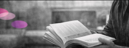 hérapeute consultant un livre ouvert, en noir et blanc, avec des formes rose et violet en arrière-plan.