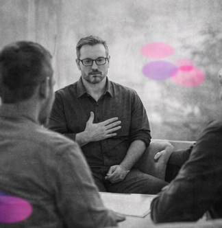 Thérapeute les yeux fermés, main posée sur le buste, en noir et blanc, avec des formes rose et violet.