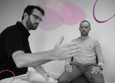 Formateur accompagnant un participant assis lors d’un atelier thérapeutique, illustrant le travail corporel et relationnel en situation clinique.