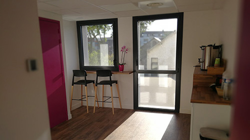 Espace pause lumineux à l’Institut Mimethys avec table haute, chaises et vue sur l’extérieur