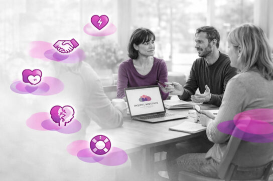 Groupe de professionnels en réunion de travail, discutant autour d’un ordinateur dans un cadre lumineux, illustrant la construction d’une formation INTRA sur mesure